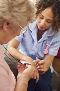 a care nurse demonstrates to a senior woman how her panic pendant would work in the event of a fall or medical emergency.